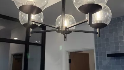 Close-up of a modern chandelier with clear globe shades and warm bulbs hanging in a community interior space.