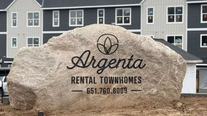 Large Rock with Argenta Townhomes logo with newly built townhomes in the background 