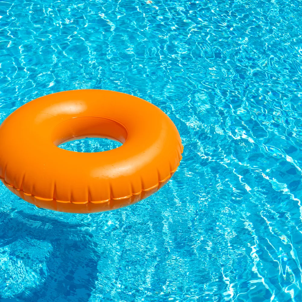 Bright orange swim ring floating in a clear, blue swimming pool.