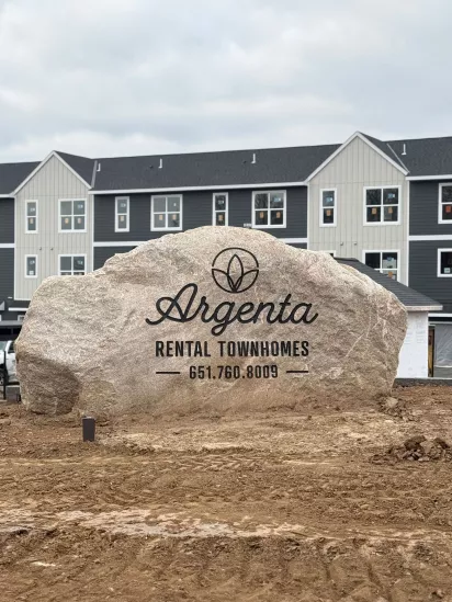 Large Rock with Argenta Townhomes logo with newly built townhomes in the background 