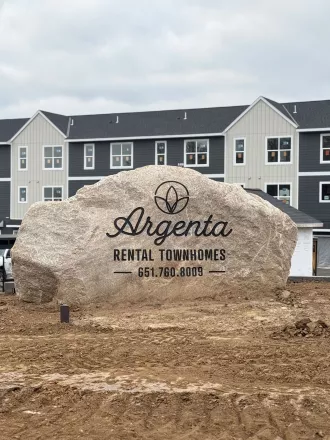 Large Rock with Argenta Townhomes logo with newly built townhomes in the background 